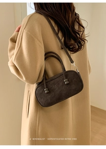 Detail of dark brown suede crossbody bag with vintage style handle and gold hardware