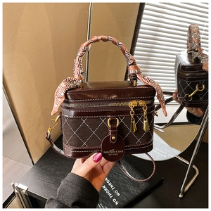 Detail van donkerbruine box bag met ruitpatroon en handvat versierd met een zijden sjaal