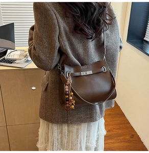 Detail of coffee leather tote bag with vintage beaded tassel and silver twist-lock closure