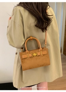 Detalle de bolso bandolera retro de ante con hebilla dorada en modelo con gabardina