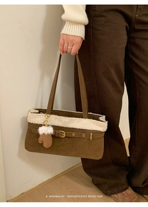 Detail of dark brown suede shoulder bag with white faux fur trim and gold buckle