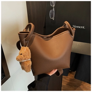 Detail of brown litchi pattern leather bucket bag with contrast stitching and bear charm