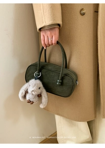 Detail of olive green suede Boston bag with double handles and a cute bunny plush charm