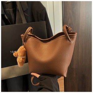 Close-up of brown lychee grain leather bucket bag with white stitching and knot handle