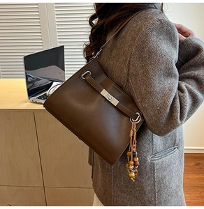 Detail of brown faux leather tote bag with silver hardware and boho beaded tassel accessory