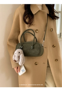 Olive green velvet Boston bag with rabbit charm styled on a wool coat outfit