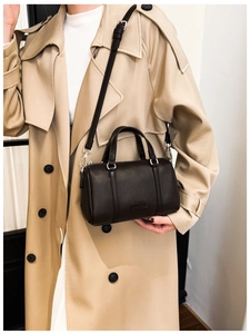 Close-up of a brown pebble leather Boston bag featuring silver metal hooks and shoulder strap