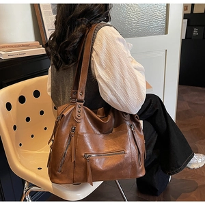 Detail of vintage brown leather tote bag with functional zippers and metal rivet hardware