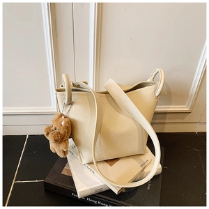 Close-up of creamy lychee textured leather bucket bag with cute brown puppy plush charm
