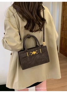 Detalle del bolso bandolera vintage en ante marrón oscuro con hebilla de corazón