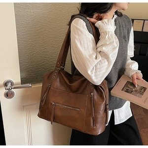 Detail of vintage brown tote bag showing multi-zipper pockets and rivet texture