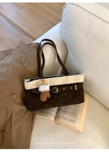 Detail of dark brown faux suede bag with plush white trim and a heart charm