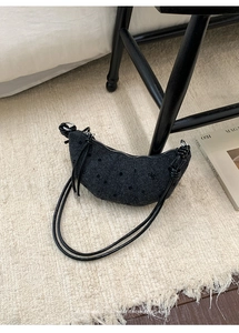 Détail du sac croissant noir avec motif étoilé et bandoulière à nœuds élégante