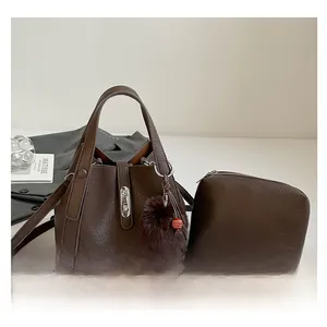 Detail of brown litchi pattern leather bucket bag set with silver clasp and fur pompom