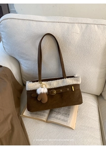 Brown suede handbag with white faux fur trim and cute glove charm on white fabric