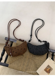 Détail de sacs demi-lune rétro à pois noirs sur tissu texturé marron et gris foncé