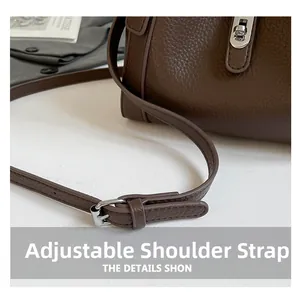Detail of adjustable shoulder strap with silver metal buckle on dark brown leather bucket bag