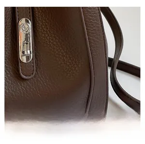 Close-up of brown bucket bag showing lychee grain texture and silver metal twist lock