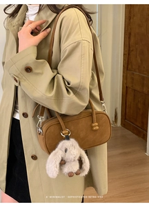 Detail of retro brown cylinder Boston bag with a cute plush bunny charm and shoulder strap