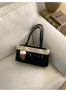 Close-up of black suede tote bag featuring white shearling trim and stylish bag charms