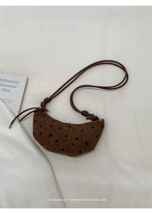 Vue de dessus d'un sac croissant marron à pois sur un tissu texturé blanc élégant