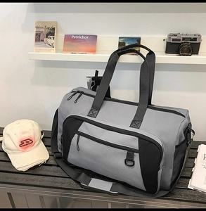 Detailed view of a grey and black travel bag on a bench with multiple zip compartments