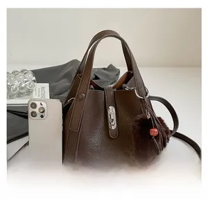 Detail view of dark brown pebbled leather tote with silver lock and size comparison to phone
