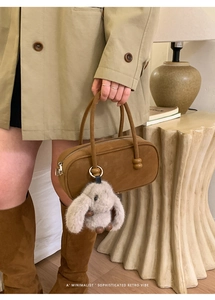 Close-up of retro brown faux suede bowling bag featuring a cute plush bunny charm