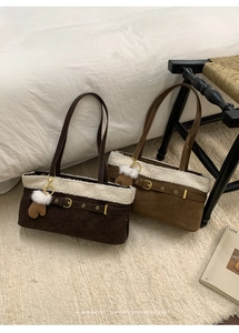 Detail of suede tote bags with white faux fur trim and heart plush charms on a soft rug