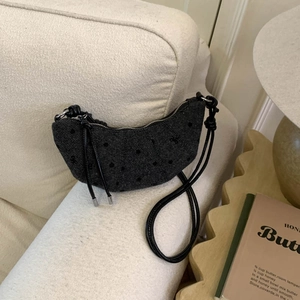 Détail du sac croissant à pois sur un canapé minimaliste à la texture raffinée