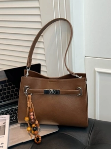 Brown leather tote bag with vintage metal lock and decorative beads on the handle
