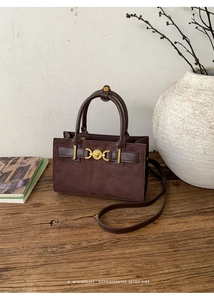 Bolso bandolera vintage de ante marrón con cierre de corazón dorado sobre madera