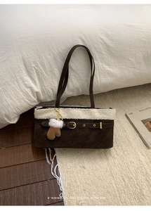 Detail of dark brown suede shoulder bag with white faux fur trim and gold buckle