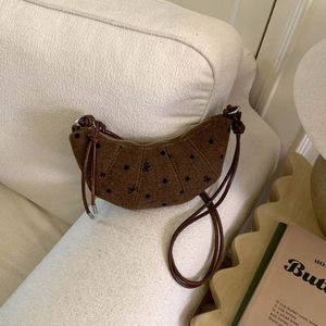Détail d'un sac croissant en tricot marron avec pois et broderie nœud noir