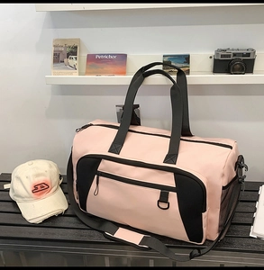Detail view of pink and black travel bag showing mesh side pocket and zipper strap