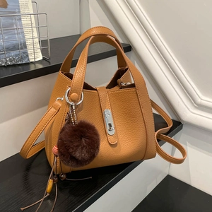 Vue détaillée du sac seau en cuir grainé caramel avec pompon en fourrure et fermoir