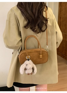 Retro brown suede barrel bag with plush rabbit charm shown on model in khaki trench coat