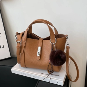 Détail du sac seau en cuir grainé marron avec fermoir argenté et pompon en peluche