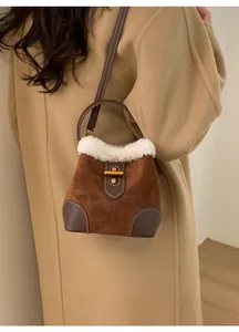 Détail d'un sac bandoulière en daim marron avec bordure en fourrure et fermoir doré chic