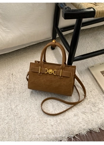 Vista detallada del bolso retro marrón oscuro con hebilla dorada sobre alfombra