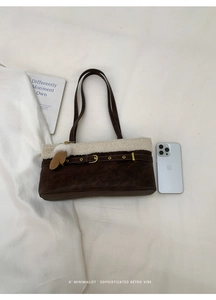 Detail of vintage brown suede shoulder bag with plush shearling trim and gold buckle