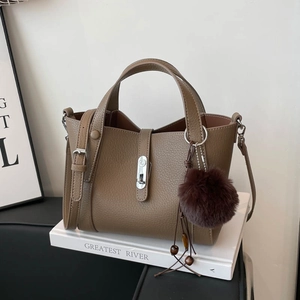 Détail du sac seau en cuir grainé marron avec fermoir argenté et pompon doux
