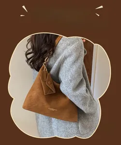 Detail of a large brown suede bucket bag with gold chain strap and mini pouch