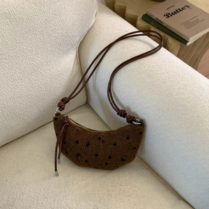 Détail du sac croissant tissé marron avec pois noirs et bandoulière à nœuds
