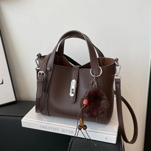 Détail d'un sac seau en cuir marron foncé avec fermoir argenté et breloque en peluche