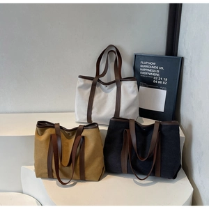 Trois grands sacs fourre-tout en toile en beige, moutarde et gris sur socles
