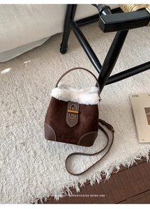 Détail du sac seau en daim rétro avec bordure en fausse fourrure blanche et fermoir laiton
