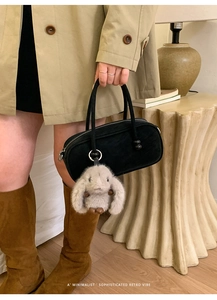 Minimalist black cylinder handbag featuring a cute plush bunny charm and silver ring detail