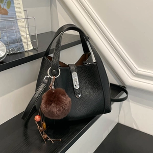 Détail du sac seau en cuir grainé noir avec boucle argentée et breloque en peluche