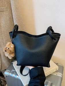 Chic black pebble leather bucket bag with white stitching and plush dog charm for women